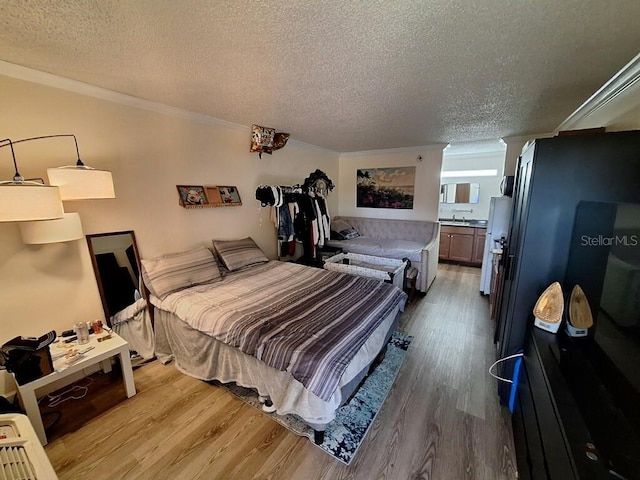 bedroom with light hardwood / wood-style flooring, a textured ceiling, and crown molding