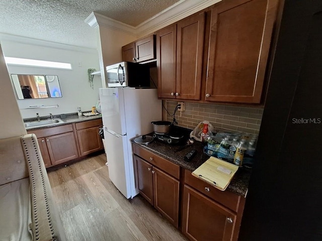 kitchen with crown molding, light hardwood / wood-style floors, sink, tasteful backsplash, and white refrigerator