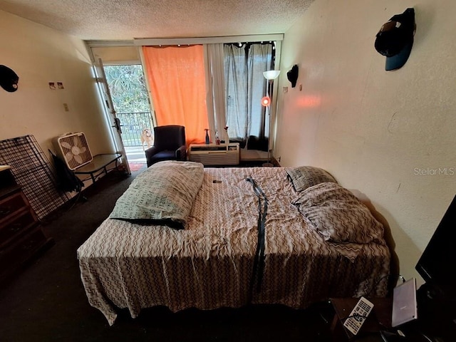 bedroom with a textured ceiling, access to exterior, and dark colored carpet