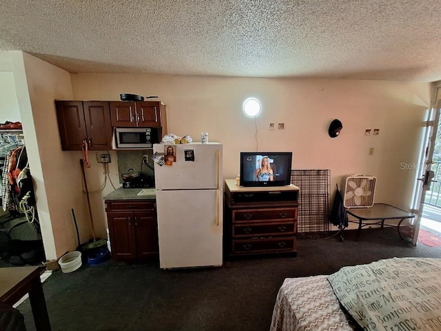 interior space with dark brown cabinets, dark colored carpet, white fridge, and stainless steel microwave