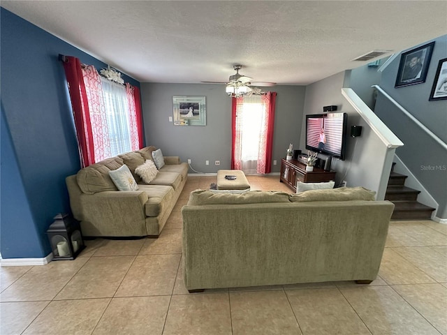 living room with a textured ceiling, light tile flooring, and ceiling fan