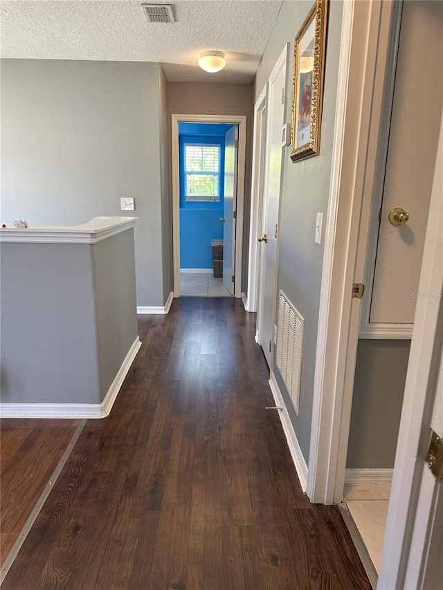 hall with a textured ceiling and dark hardwood / wood-style floors