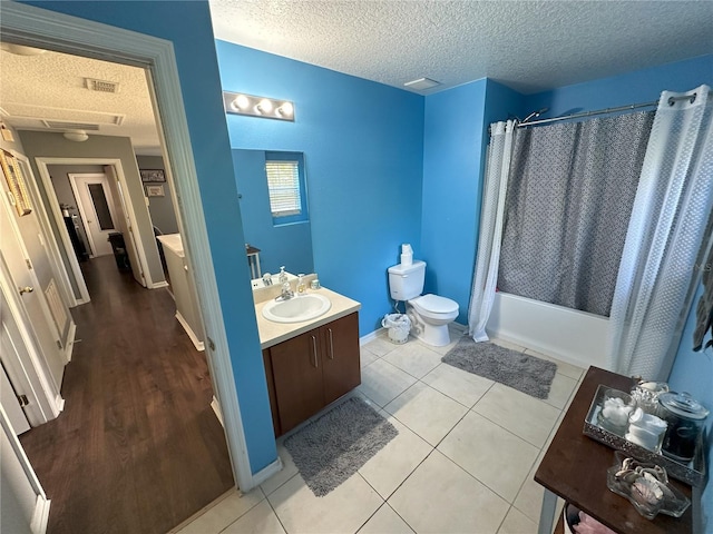 full bathroom featuring toilet, oversized vanity, shower / bath combo with shower curtain, a textured ceiling, and tile floors