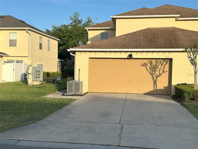 view of front of property featuring a front yard, a garage, and central AC unit