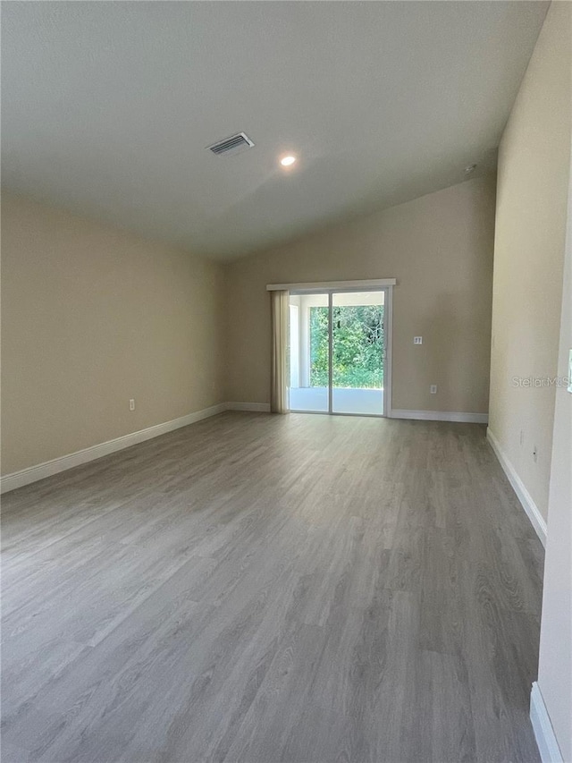 empty room featuring lofted ceiling and light hardwood / wood-style flooring