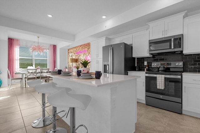 kitchen featuring a kitchen island, stainless steel appliances, white cabinets, and a chandelier