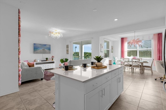 kitchen with an inviting chandelier, a center island, white cabinetry, and light tile flooring