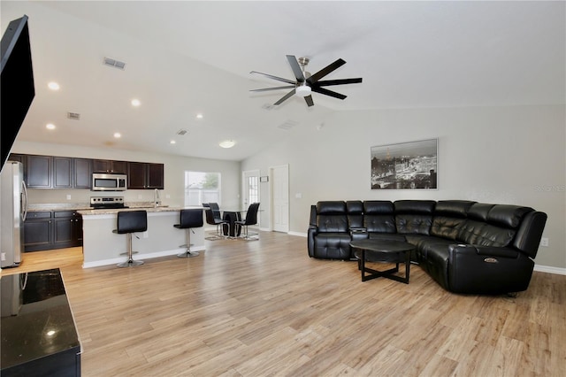 living room featuring ceiling fan, light wood-type flooring, and vaulted ceiling