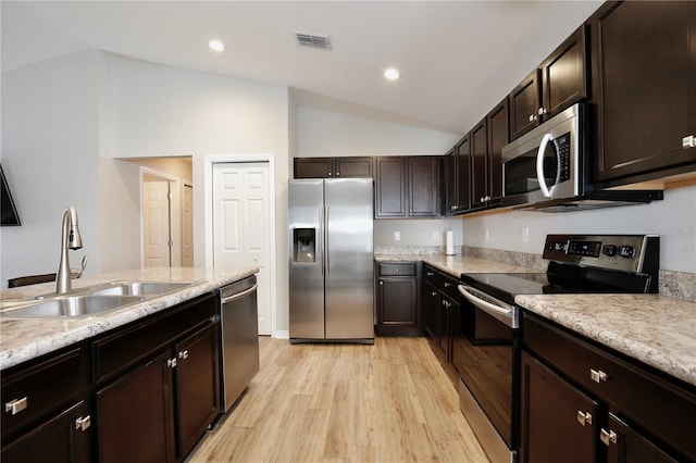 kitchen with stainless steel appliances, vaulted ceiling, dark brown cabinets, light wood-type flooring, and sink