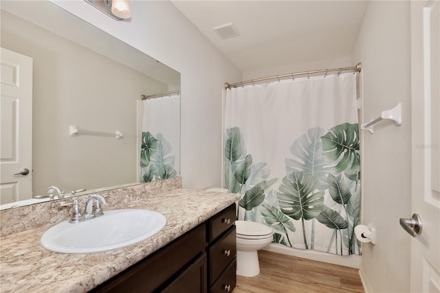 bathroom with wood-type flooring, toilet, and oversized vanity