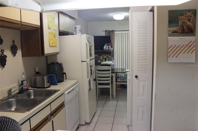 kitchen featuring light tile floors, white cabinets, dishwasher, and sink