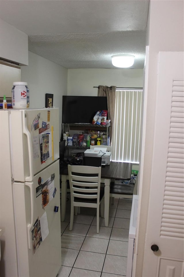 kitchen featuring light tile floors, a textured ceiling, and white fridge