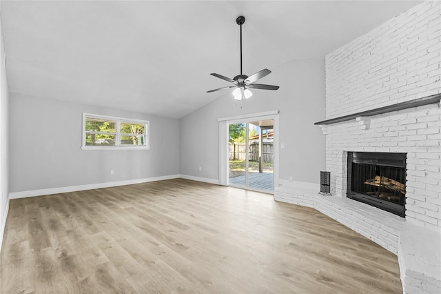 unfurnished living room with vaulted ceiling, ceiling fan, a brick fireplace, and light hardwood / wood-style flooring