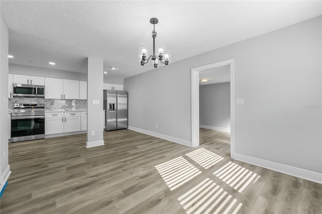 interior space with a chandelier, light hardwood / wood-style floors, and a textured ceiling