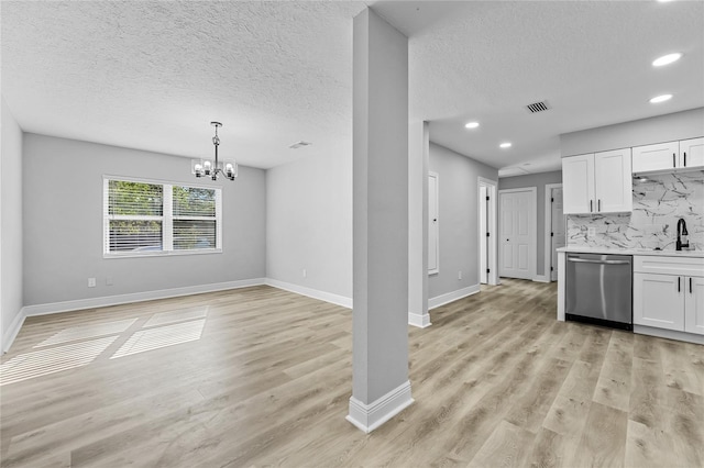 kitchen with an inviting chandelier, white cabinetry, stainless steel dishwasher, and light wood-type flooring