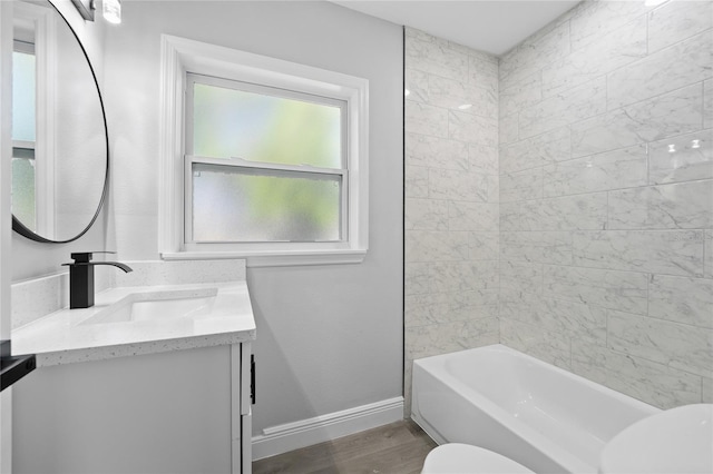 full bathroom featuring tiled shower / bath, toilet, vanity, and hardwood / wood-style flooring