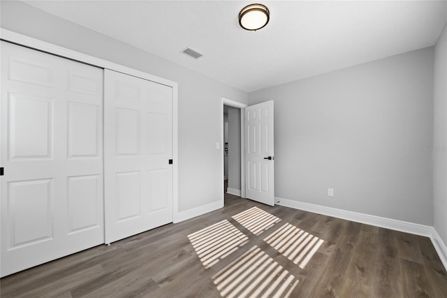 unfurnished bedroom featuring dark hardwood / wood-style flooring and a closet