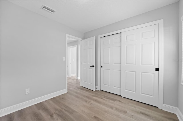 unfurnished bedroom with a closet and light hardwood / wood-style floors