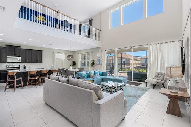 living room with light tile flooring, a healthy amount of sunlight, and a towering ceiling