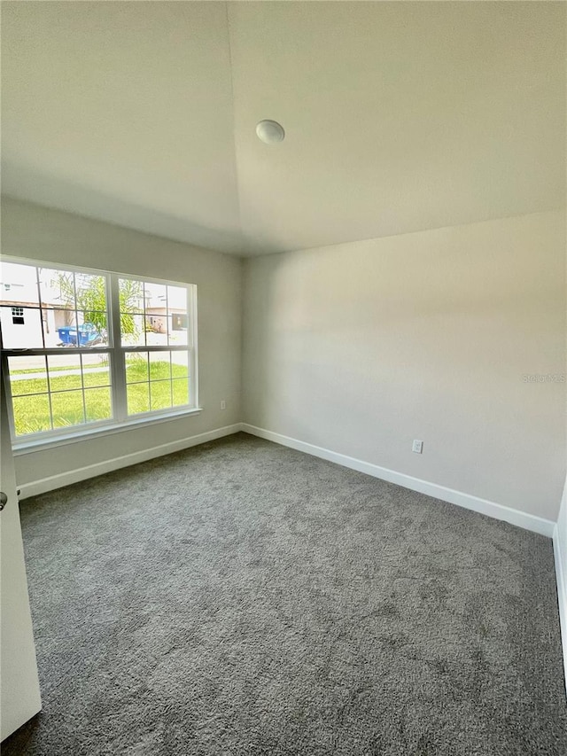 carpeted spare room with lofted ceiling