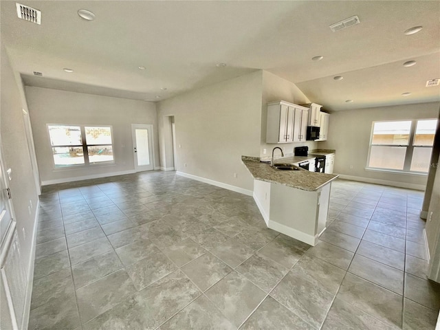 kitchen featuring light tile floors, kitchen peninsula, white cabinetry, sink, and light stone counters