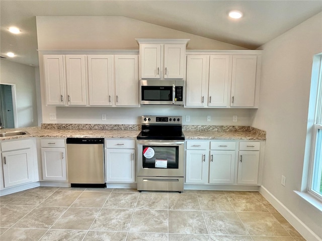 kitchen with light tile flooring, white cabinets, appliances with stainless steel finishes, and vaulted ceiling