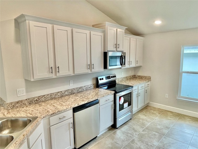 kitchen featuring lofted ceiling, a wealth of natural light, appliances with stainless steel finishes, and white cabinetry