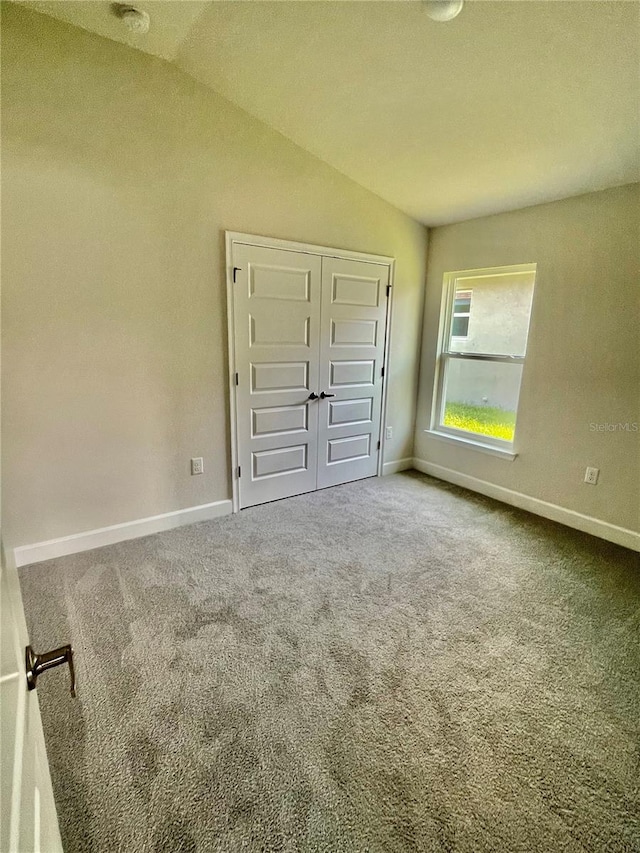 unfurnished bedroom featuring carpet flooring, a closet, and vaulted ceiling