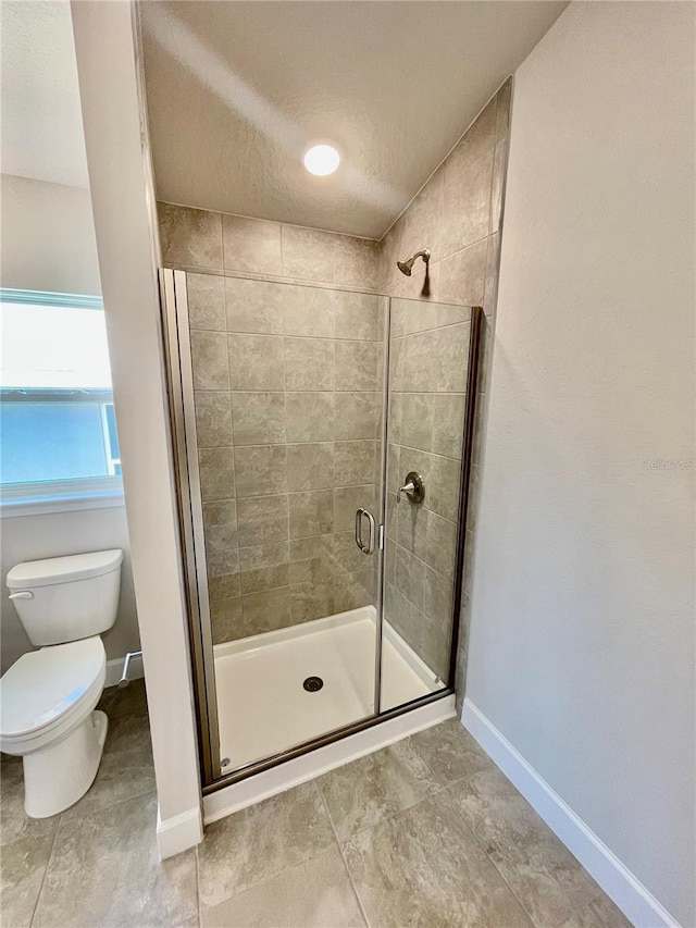 bathroom featuring walk in shower, toilet, a textured ceiling, and tile flooring