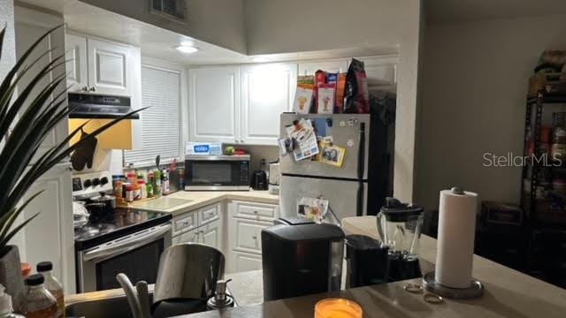 kitchen featuring range hood, stainless steel appliances, and white cabinetry