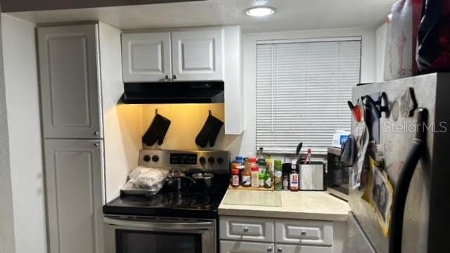 kitchen with white cabinets, refrigerator, electric range, and fume extractor