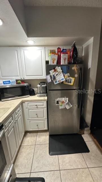 kitchen with white cabinets, light tile flooring, and stainless steel appliances