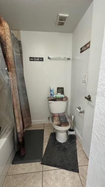 bathroom with toilet, shower / bath combo with shower curtain, and tile flooring