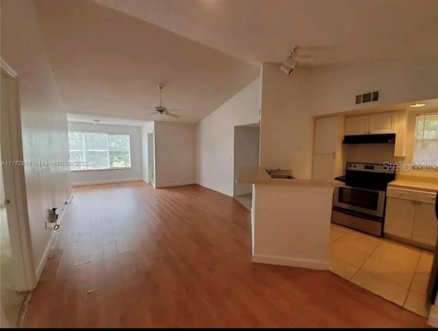 kitchen with light tile flooring, ceiling fan, high vaulted ceiling, and stainless steel range with electric stovetop