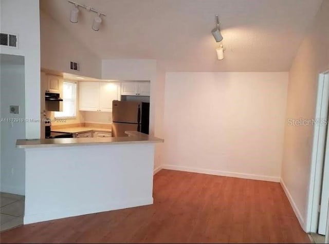 kitchen featuring rail lighting, stainless steel refrigerator, white cabinetry, and light wood-type flooring