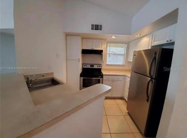 kitchen with white cabinets, range, sink, and stainless steel refrigerator