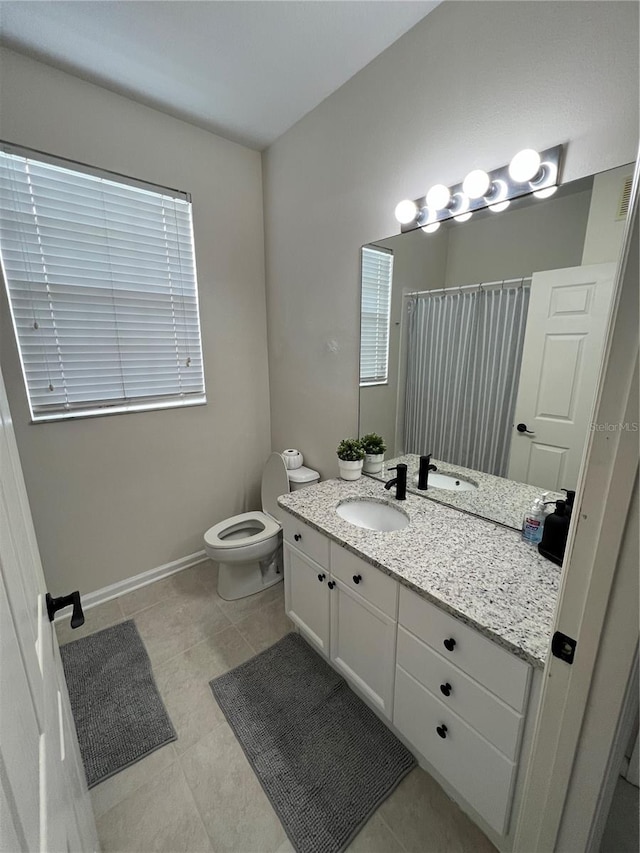 bathroom with toilet, vanity, and tile flooring