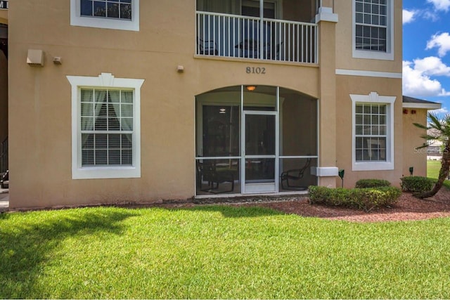 back of house featuring a balcony and a lawn