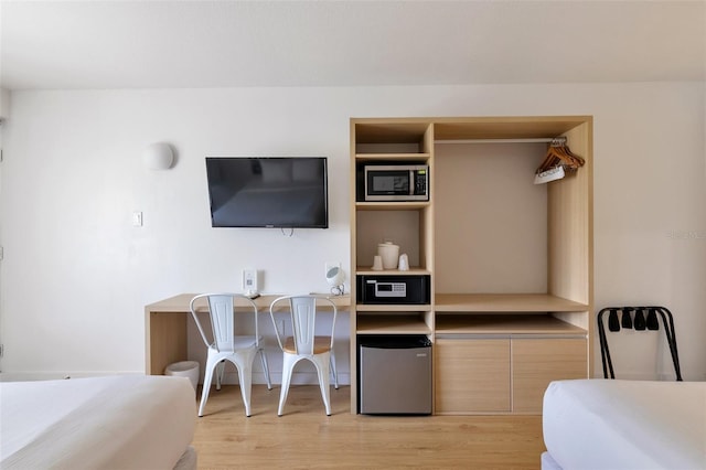 bedroom featuring light wood-type flooring and fridge