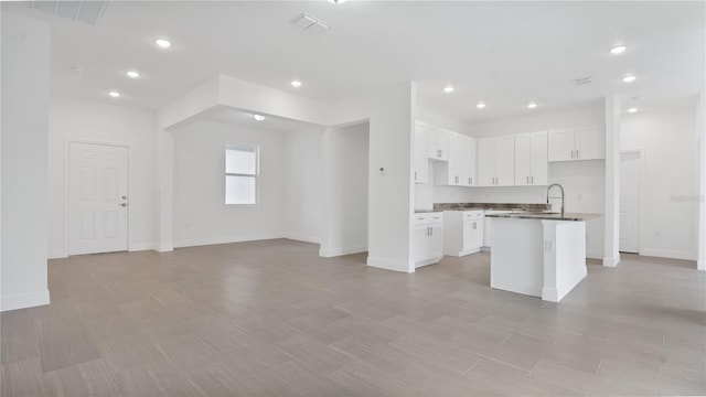 kitchen featuring white cabinets, a center island with sink, and sink