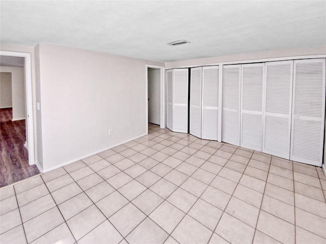 unfurnished bedroom featuring light tile patterned flooring and two closets