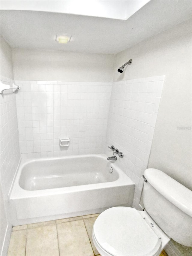 bathroom with tile patterned flooring, toilet, and tiled shower / bath