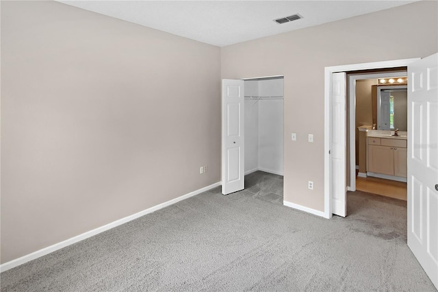 unfurnished bedroom featuring light colored carpet, sink, and a closet