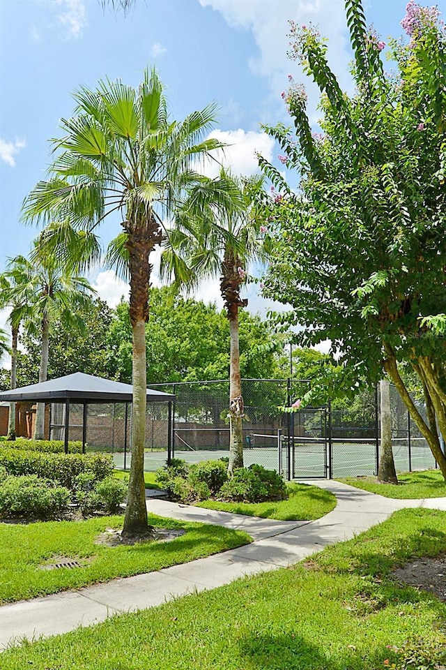 view of home's community with a yard and tennis court