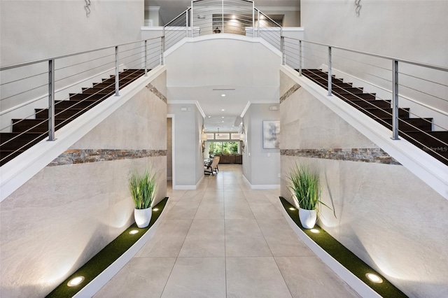 interior space featuring ornamental molding, light tile flooring, and a towering ceiling