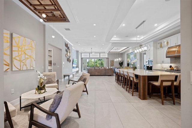 interior space with a raised ceiling, ornamental molding, and a notable chandelier