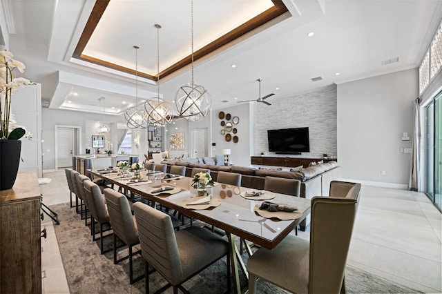 tiled dining space with plenty of natural light, ceiling fan with notable chandelier, a raised ceiling, and ornamental molding