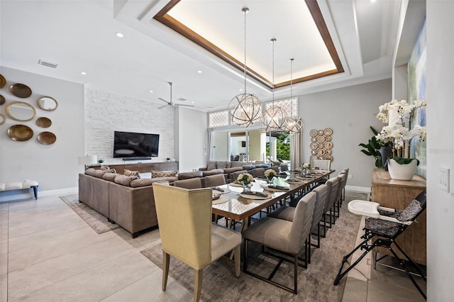 dining area with a tray ceiling, light tile floors, and ceiling fan with notable chandelier