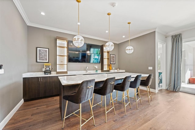 kitchen featuring decorative light fixtures, a center island, light stone counters, dark brown cabinets, and hardwood / wood-style flooring