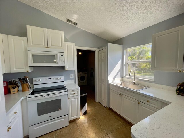 kitchen with lofted ceiling, light tile floors, white appliances, white cabinets, and sink